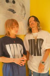 「UK.PROJECT POSTER EXHIBITION 1999-2026」で販売されるUK.PROJECT初となるオフィシャルTシャツを着用した伊澤彩織（左）と庄村聡泰（右）。（撮影：芦沢洋介）